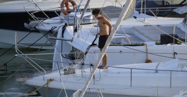 İtalya, Sicilya, Akdeniz, Marina di Ragusa (Ragusa ili); 30 Ağustos 2025; limanda lüks bir yatı temizleyen adam - EDITORIAL