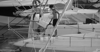 İtalya, Sicilya, Akdeniz, Marina di Ragusa (Ragusa ili); 30 Ağustos 2025; limanda lüks bir yatı temizleyen adam - EDITORIAL