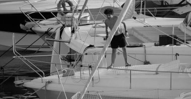 İtalya, Sicilya, Akdeniz, Marina di Ragusa (Ragusa ili); 30 Ağustos 2025; limanda lüks bir yatı temizleyen adam - EDITORIAL