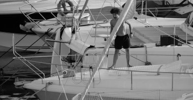 İtalya, Sicilya, Akdeniz, Marina di Ragusa (Ragusa ili); 30 Ağustos 2025; limanda lüks bir yatı temizleyen adam - EDITORIAL