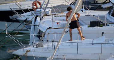 İtalya, Sicilya, Akdeniz, Marina di Ragusa (Ragusa Eyaleti), limanda lüks bir yatı temizleyen adam 