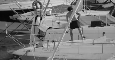 İtalya, Sicilya, Akdeniz, Marina di Ragusa (Ragusa Eyaleti), limanda lüks bir yatı temizleyen adam 