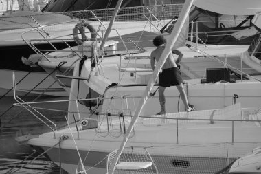 İtalya, Sicilya, Akdeniz, Marina di Ragusa (Ragusa Eyaleti), limanda lüks bir yatı temizleyen adam 