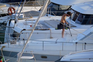 İtalya, Sicilya, Akdeniz, Marina di Ragusa (Ragusa ili); 30 Ağustos 2025; limanda lüks bir yatı temizleyen adam - EDITORIAL