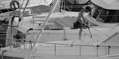 İtalya, Sicilya, Akdeniz, Marina di Ragusa (Ragusa ili); 30 Ağustos 2025; limanda lüks bir yatı temizleyen adam - EDITORIAL