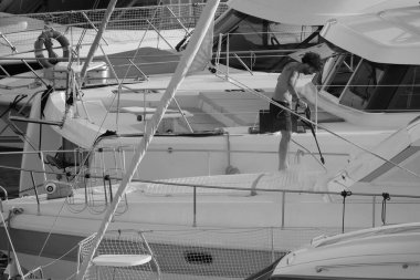 İtalya, Sicilya, Akdeniz, Marina di Ragusa (Ragusa ili); 30 Ağustos 2025; limanda lüks bir yatı temizleyen adam - EDITORIAL