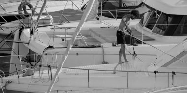 İtalya, Sicilya, Akdeniz, Marina di Ragusa (Ragusa ili); 30 Ağustos 2025; limanda lüks bir yatı temizleyen adam - EDITORIAL