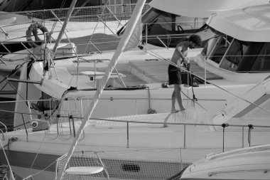 İtalya, Sicilya, Akdeniz, Marina di Ragusa (Ragusa ili); 30 Ağustos 2025; limanda lüks bir yatı temizleyen adam - EDITORIAL