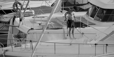 İtalya, Sicilya, Akdeniz, Marina di Ragusa (Ragusa ili); 30 Ağustos 2025; limanda lüks bir yatı temizleyen adam - EDITORIAL