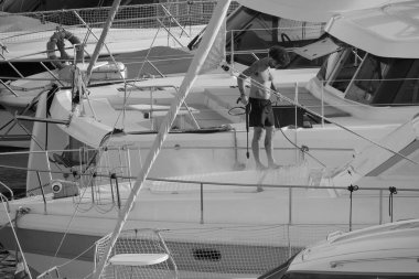 İtalya, Sicilya, Akdeniz, Marina di Ragusa (Ragusa ili); 30 Ağustos 2025; limanda lüks bir yatı temizleyen adam - EDITORIAL