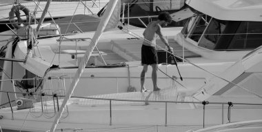 İtalya, Sicilya, Akdeniz, Marina di Ragusa (Ragusa ili); 30 Ağustos 2025; limanda lüks bir yatı temizleyen adam - EDITORIAL