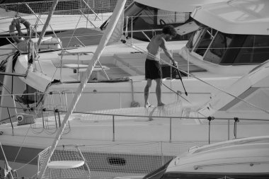 İtalya, Sicilya, Akdeniz, Marina di Ragusa (Ragusa ili); 30 Ağustos 2025; limanda lüks bir yatı temizleyen adam - EDITORIAL