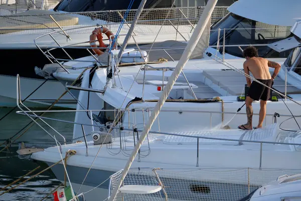 İtalya, Sicilya, Akdeniz, Marina di Ragusa (Ragusa ili); 30 Ağustos 2025; limanda lüks bir yatı temizleyen adam - EDITORIAL