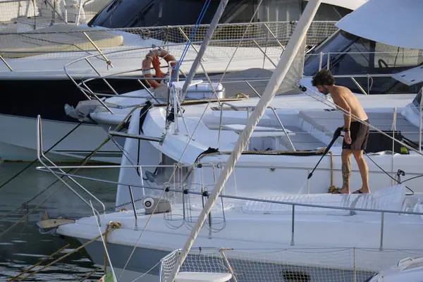 İtalya, Sicilya, Akdeniz, Marina di Ragusa (Ragusa ili); 30 Ağustos 2025; limanda lüks bir yatı temizleyen adam - EDITORIAL