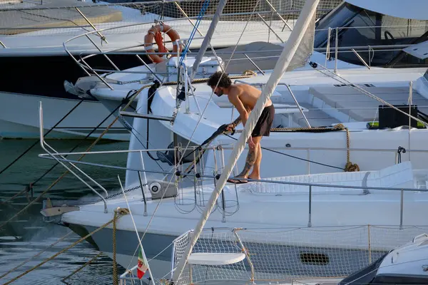 İtalya, Sicilya, Akdeniz, Marina di Ragusa (Ragusa ili); 30 Ağustos 2025; limanda lüks bir yatı temizleyen adam - EDITORIAL