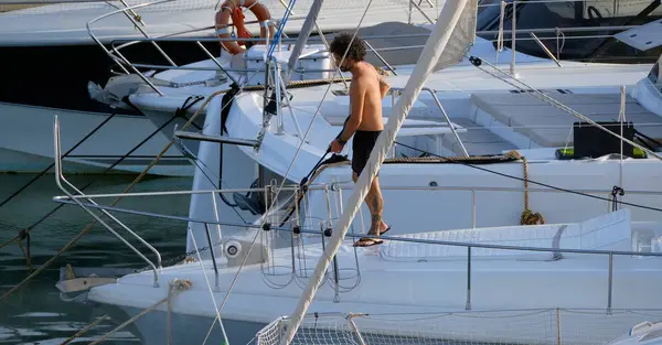 İtalya, Sicilya, Akdeniz, Marina di Ragusa (Ragusa ili); 30 Ağustos 2025; limanda lüks bir yatı temizleyen adam - EDITORIAL