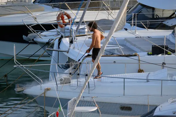 İtalya, Sicilya, Akdeniz, Marina di Ragusa (Ragusa ili); 30 Ağustos 2025; limanda lüks bir yatı temizleyen adam - EDITORIAL