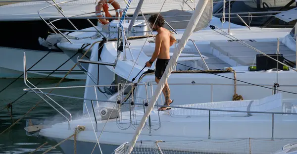 İtalya, Sicilya, Akdeniz, Marina di Ragusa (Ragusa ili); 30 Ağustos 2025; limanda lüks bir yatı temizleyen adam - EDITORIAL