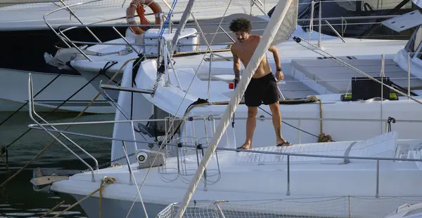 İtalya, Sicilya, Akdeniz, Marina di Ragusa (Ragusa ili); 30 Ağustos 2025; limanda lüks bir yatı temizleyen adam - EDITORIAL