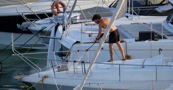 İtalya, Sicilya, Akdeniz, Marina di Ragusa (Ragusa ili); 30 Ağustos 2025; limanda lüks bir yatı temizleyen adam - EDITORIAL