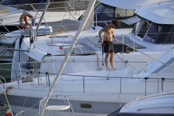 İtalya, Sicilya, Akdeniz, Marina di Ragusa (Ragusa ili); 30 Ağustos 2025; limanda lüks bir yatı temizleyen adam - EDITORIAL