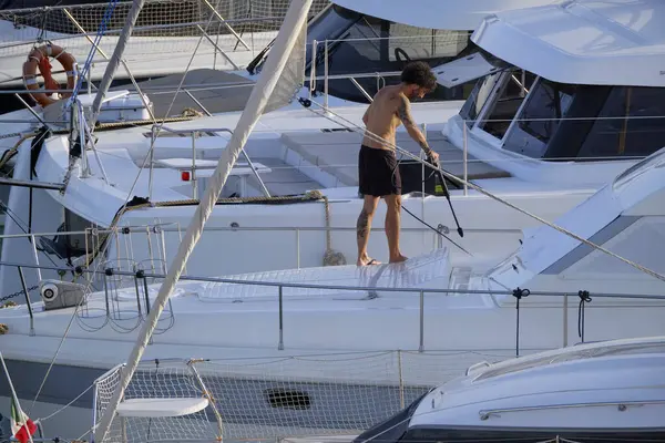 İtalya, Sicilya, Akdeniz, Marina di Ragusa (Ragusa ili); 30 Ağustos 2025; limanda lüks bir yatı temizleyen adam - EDITORIAL