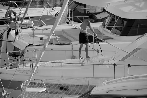 İtalya, Sicilya, Akdeniz, Marina di Ragusa (Ragusa ili); 30 Ağustos 2025; limanda lüks bir yatı temizleyen adam - EDITORIAL