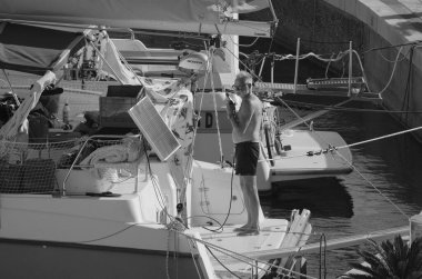 İtalya, Sicilya, Akdeniz, Marina di Ragusa (Ragusa Eyaleti); 31 Ağustos 2025, limanda katamaran yelkenli teknesini temizleyen adam - EDITORIAL