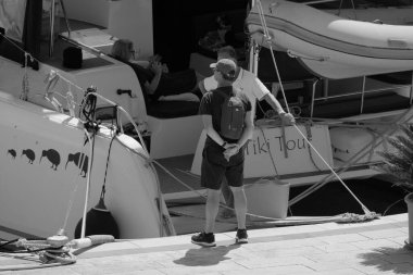 İtalya, Sicilya, Akdeniz, Marina di Ragusa (Ragusa Eyaleti); 1 Eylül 2025, limandaki katamaran yelkenli teknesinde insanlar - EDITORIAL