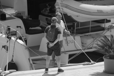 İtalya, Sicilya, Akdeniz, Marina di Ragusa (Ragusa Eyaleti); 1 Eylül 2025, limandaki katamaran yelkenli teknesinde insanlar - EDITORIAL