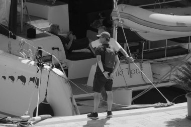 İtalya, Sicilya, Akdeniz, Marina di Ragusa (Ragusa Eyaleti); 1 Eylül 2025, limandaki katamaran yelkenli teknesinde insanlar - EDITORIAL