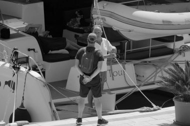 İtalya, Sicilya, Akdeniz, Marina di Ragusa (Ragusa Eyaleti); 1 Eylül 2025, limandaki katamaran yelkenli teknesinde insanlar - EDITORIAL