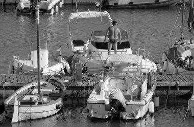 İtalya, Sicilya, Akdeniz, Marina di Ragusa (Ragusa Eyaleti), limandaki büyük kauçuk bir teknede erkekler