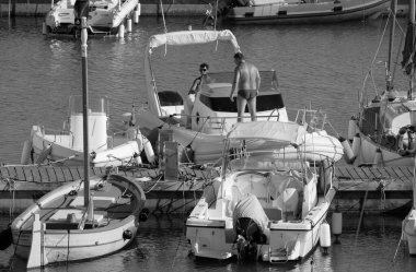 İtalya, Sicilya, Akdeniz, Marina di Ragusa (Ragusa Eyaleti); 1 Eylül 2025, limanda büyük bir kauçuk teknede erkekler - EDITORIAL