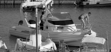 İtalya, Sicilya, Akdeniz, Marina di Ragusa (Ragusa Eyaleti); 1 Eylül 2025, limanda büyük bir kauçuk teknede erkekler - EDITORIAL