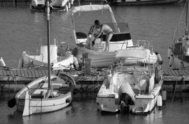 İtalya, Sicilya, Akdeniz, Marina di Ragusa (Ragusa Eyaleti); 1 Eylül 2025, limanda büyük bir kauçuk teknede erkekler - EDITORIAL