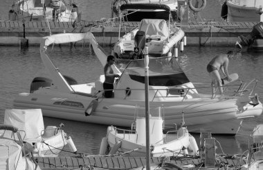 İtalya, Sicilya, Akdeniz, Marina di Ragusa (Ragusa Eyaleti); 1 Eylül 2025, limanda büyük bir kauçuk teknede erkekler - EDITORIAL