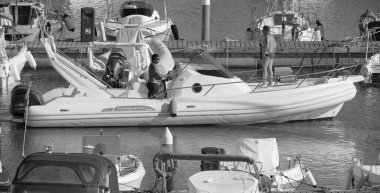 İtalya, Sicilya, Akdeniz, Marina di Ragusa (Ragusa Eyaleti); 1 Eylül 2025, limanda büyük bir kauçuk teknede erkekler - EDITORIAL