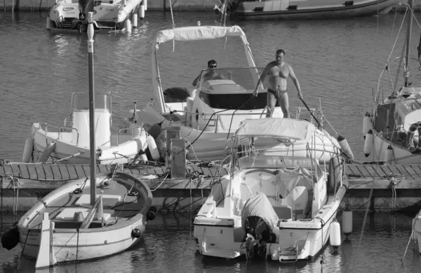 İtalya, Sicilya, Akdeniz, Marina di Ragusa (Ragusa Eyaleti); 1 Eylül 2025, limanda büyük bir kauçuk teknede erkekler - EDITORIAL