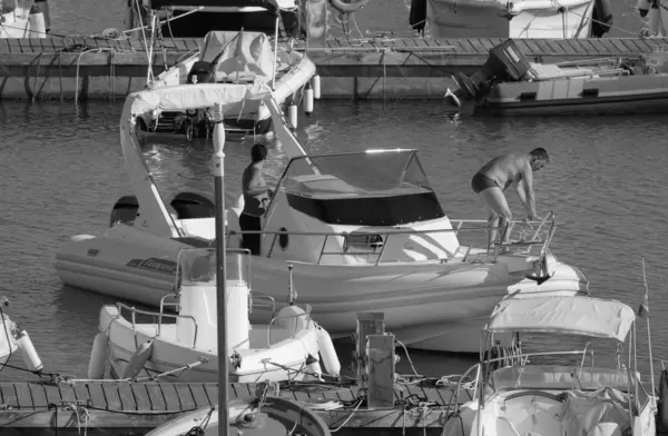 İtalya, Sicilya, Akdeniz, Marina di Ragusa (Ragusa Eyaleti); 1 Eylül 2025, limanda büyük bir kauçuk teknede erkekler - EDITORIAL