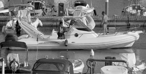 İtalya, Sicilya, Akdeniz, Marina di Ragusa (Ragusa Eyaleti); 1 Eylül 2025, limanda büyük bir kauçuk teknede erkekler - EDITORIAL