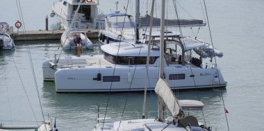 İtalya, Sicilya, Akdeniz, Marina di Ragusa (Ragusa Eyaleti); 26 Eylül 2025, limanda bir katamaran yelkenli teknesinde çift - EDITORIAL