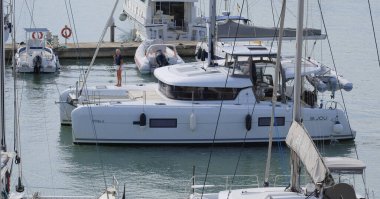 İtalya, Sicilya, Akdeniz, Marina di Ragusa (Ragusa Eyaleti); 26 Eylül 2025, limanda bir katamaran yelkenli teknesinde çift - EDITORIAL