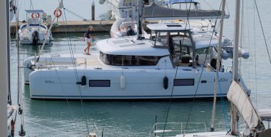 İtalya, Sicilya, Akdeniz, Marina di Ragusa (Ragusa Eyaleti); 26 Eylül 2025, limanda bir katamaran yelkenli teknesinde çift - EDITORIAL