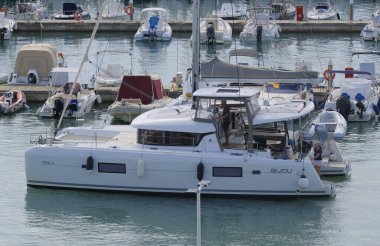 İtalya, Sicilya, Akdeniz, Marina di Ragusa (Ragusa Eyaleti); 26 Eylül 2025, limanda bir katamaran yelkenli teknesinde çift - EDITORIAL