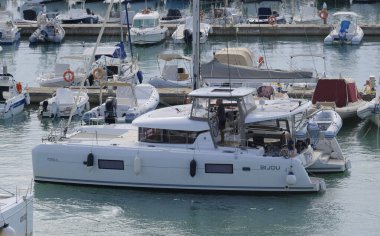 İtalya, Sicilya, Akdeniz, Marina di Ragusa (Ragusa Eyaleti); 26 Eylül 2025, limanda bir katamaran yelkenli teknesinde çift - EDITORIAL