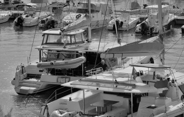 İtalya, Sicilya, Akdeniz, Marina di Ragusa (Ragusa Eyaleti); 26 Eylül 2025, limanda bir katamaran yelkenli teknesinde çift - EDITORIAL