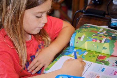 İtalya, Sicilya; 9 yaşındaki erkek çocuk ödevini evde bir masada yapıyor.