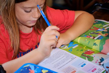 İtalya, Sicilya; 9 yaşındaki erkek çocuk ödevini evde bir masada yapıyor.