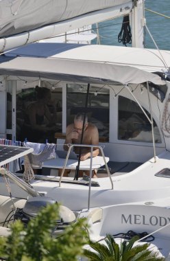 İtalya, Sicilya, Akdeniz, Marina di Ragusa (Ragusa Eyaleti); 30 Eylül 2025, limanda bir katamaran yelkenli teknesinde çift - EDITORIAL